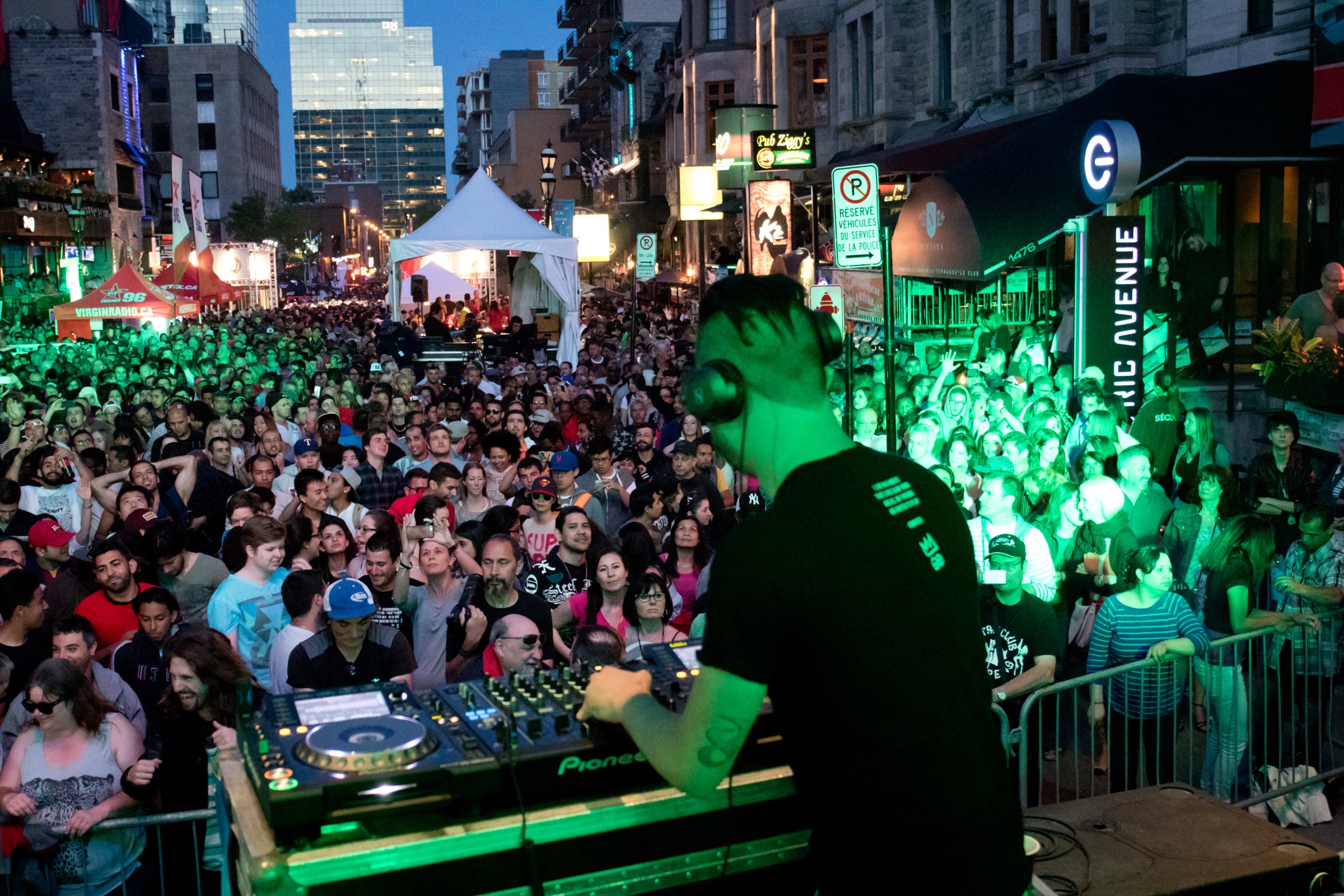 Grand Prix F1 weekend on Crescent Street, Montreal — DJ at decks, crowd lit in green, downtown skyline behind — © Susan Moss Photography, Tourisme Montréal