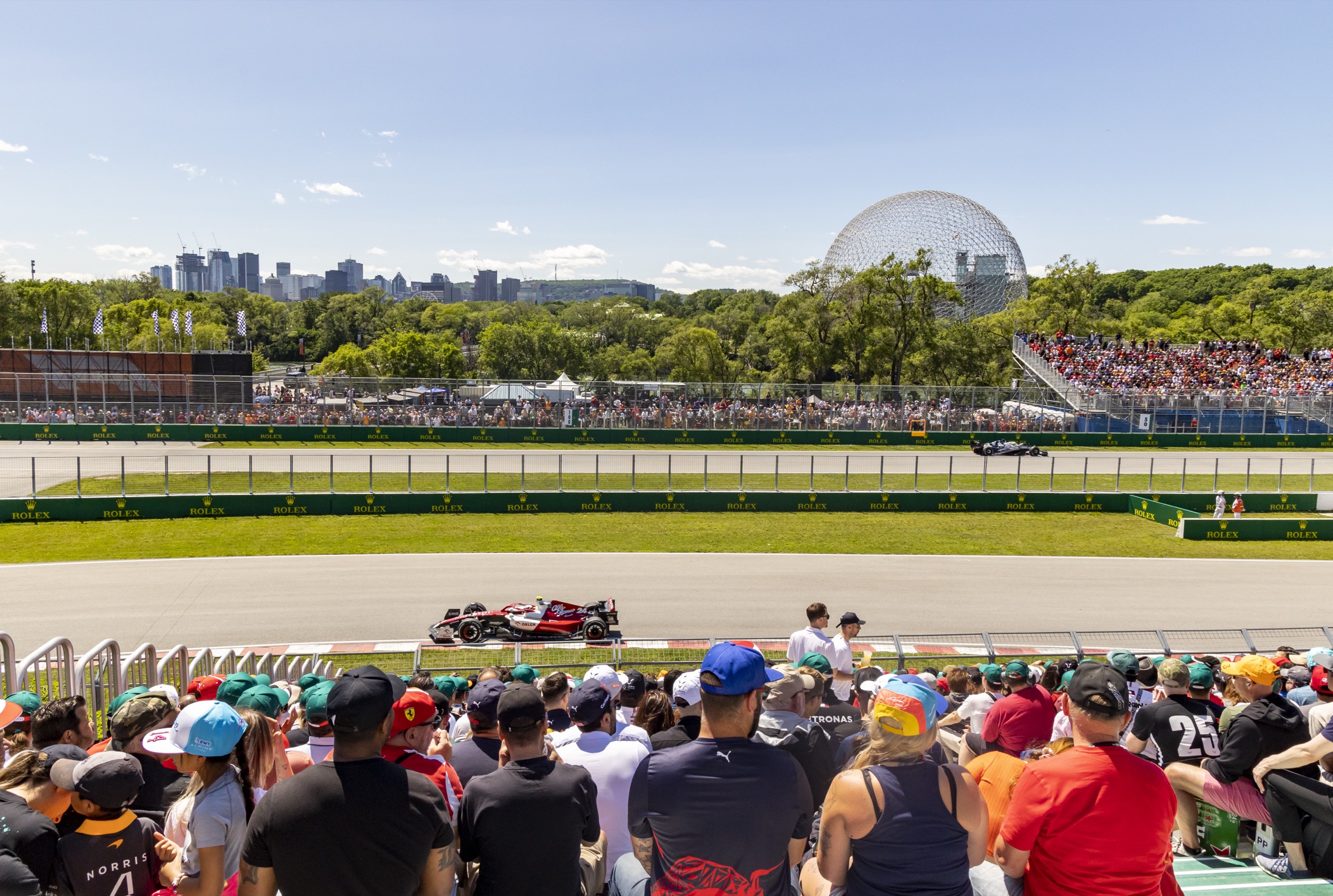F1 Grand Prix at Circuit Gilles-Villeneuve — large American flag visible in the crowd, Biosphere geodesic dome in background, race weekend energy — © Eva Blue, Tourisme Montréal